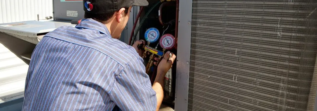 HVAC technician servicing a condenser unit in Fairborn